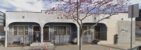 A white building with a tree in front of it.