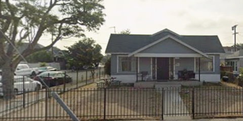 A small house with a black fence in front.