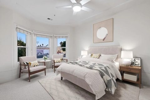A bedroom with a large bed, a chair, and a window overlooking a cityscape.