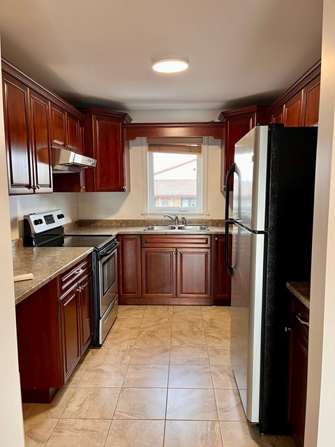 A kitchen with brown cabinets and a black refrigerator.