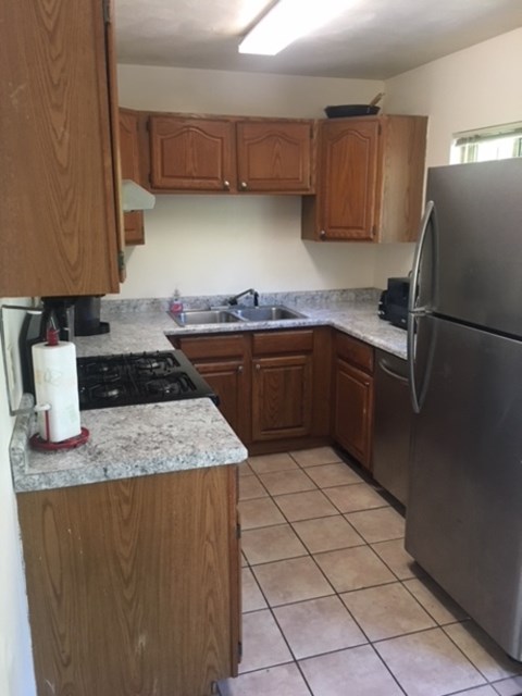 A kitchen with wooden cabinets and a stainless steel refrigerator.