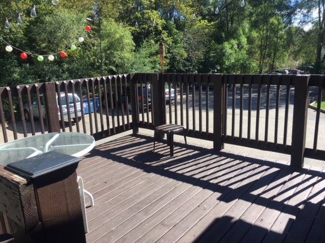 A wooden deck with a hot tub and bench.