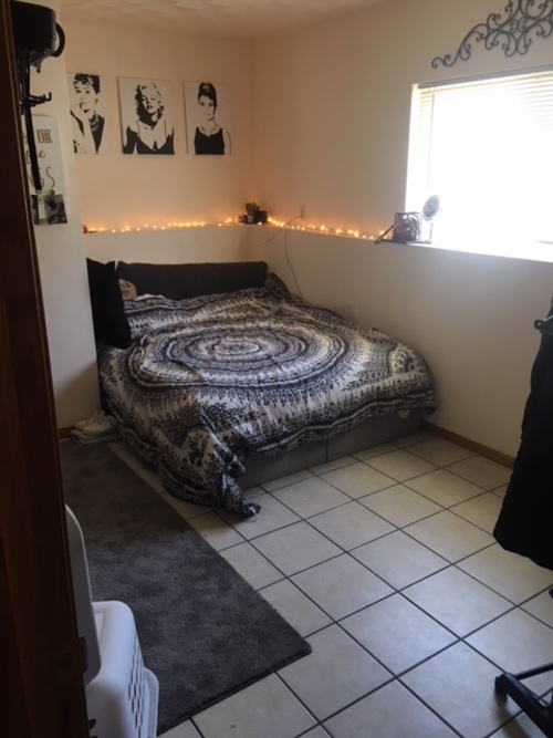 A bedroom with a bed, a rug, and pictures on the wall.