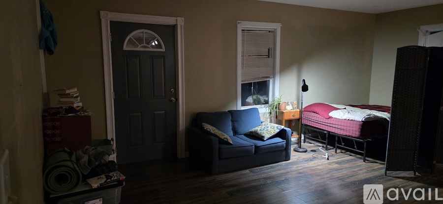 A bedroom with a bed, couch, and a door.
