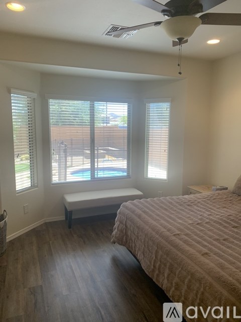 A bedroom with a bed, a bench, and a ceiling fan.