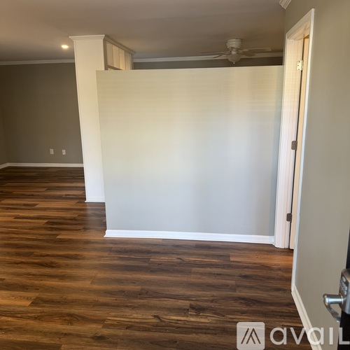 A room with wooden flooring and white walls.