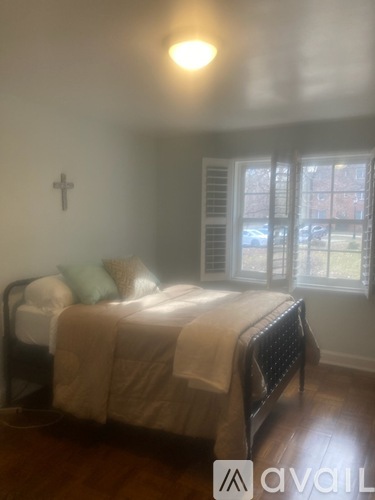 A bedroom with a bed and a cross on the wall.