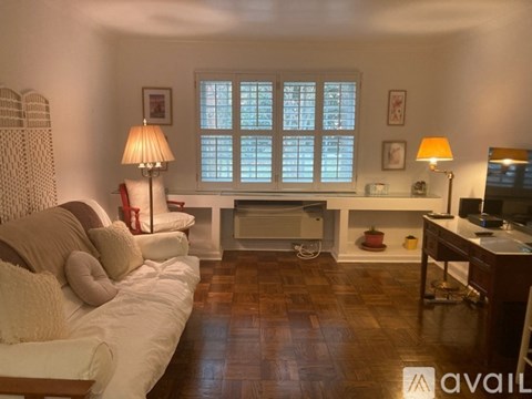 A living room with a white couch and a wooden floor.