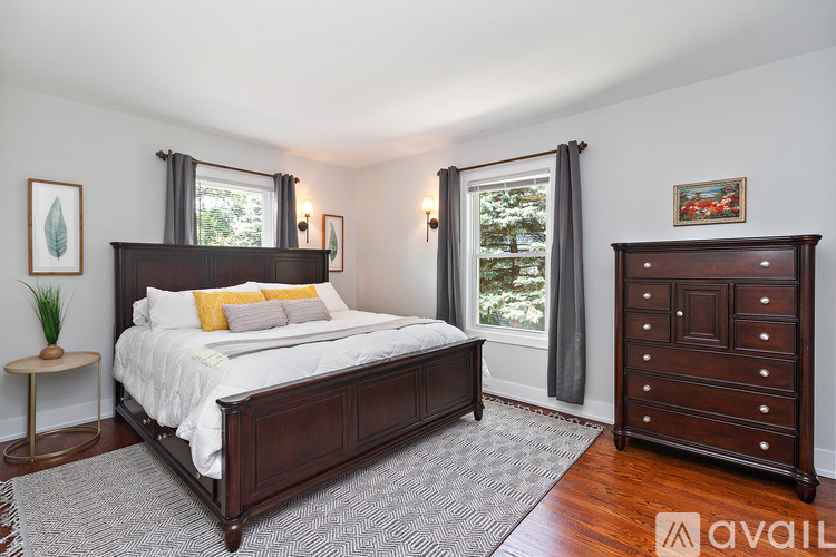 A bedroom with a large bed and a wooden dresser.