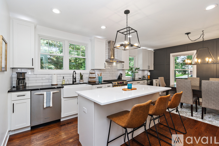 A kitchen with white cabinets and a large island with chairs around it.