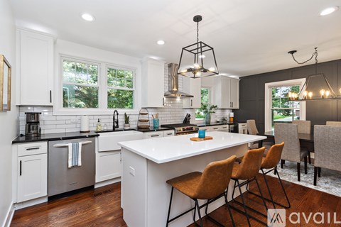 A kitchen with white cabinets and a large island with chairs around it.
