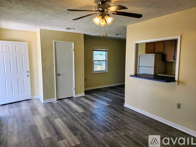 A room with a ceiling fan and wooden flooring.