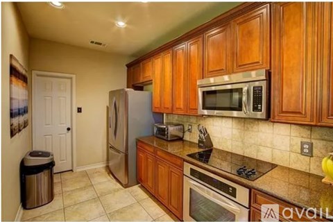 A kitchen with wooden cabinets and a stainless steel refrigerator.