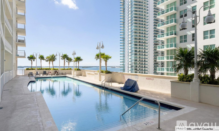 A pool area with lounge chairs and palm trees in front of a high-rise building.