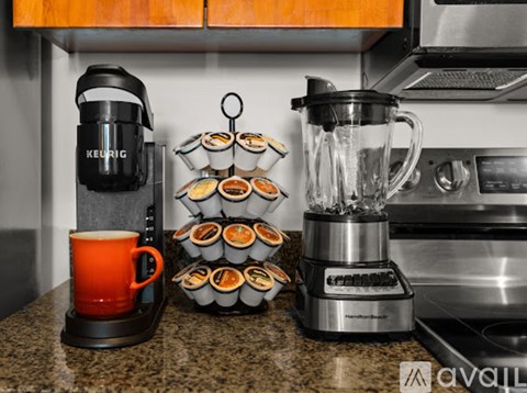 A kitchen counter with a coffee maker, a blender, and a tray of cupcakes.