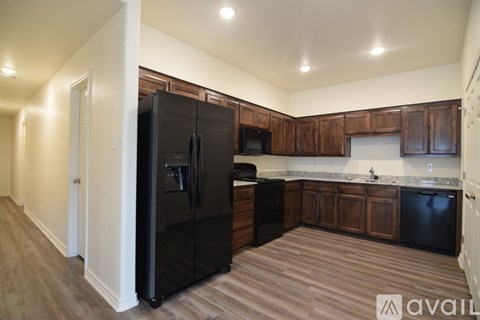 A kitchen with a black fridge and wooden cabinets.