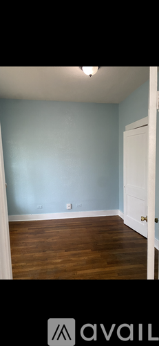 A room with a light blue wall and wooden flooring.
