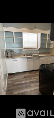 A kitchen with white cabinets and a window.