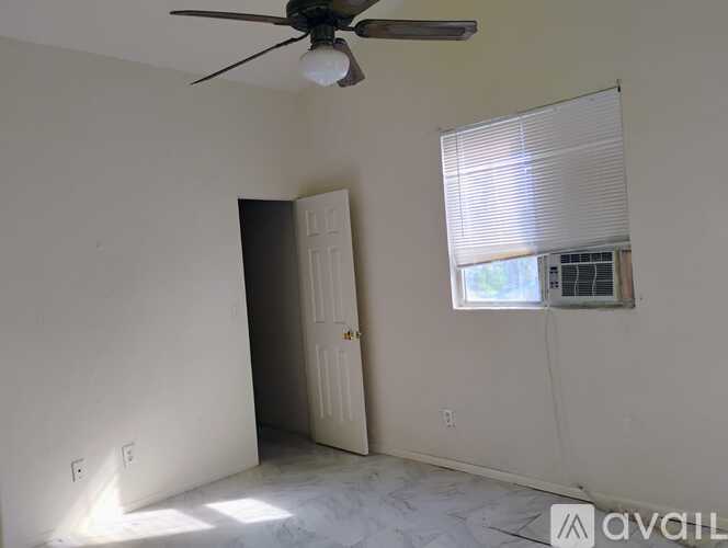 A room with a ceiling fan and a window with blinds.