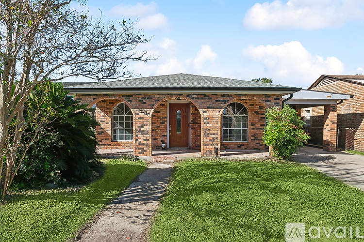 A house with a brick facade and a green lawn in front.