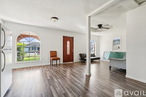 A spacious living room with wood flooring and a ceiling fan.
