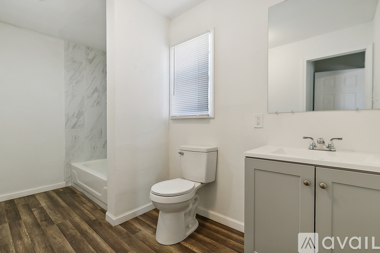 A bathroom with a toilet, sink, and mirror.