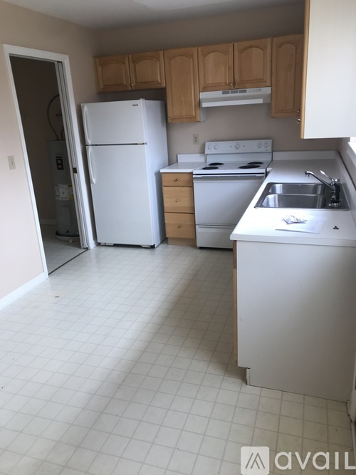 A kitchen with white appliances and wooden cabinets.