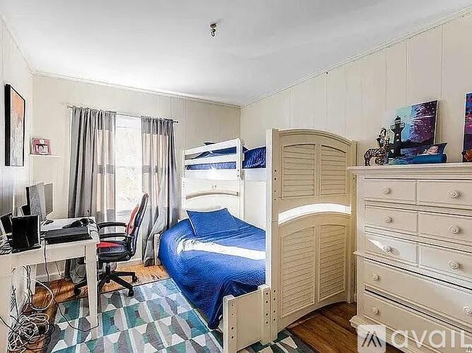 A bedroom with a bunk bed and a desk with a computer.