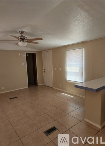 A room with a ceiling fan and a window with blinds.