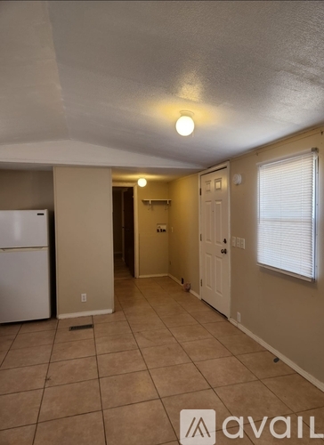 A kitchen with a white refrigerator and a tiled floor.