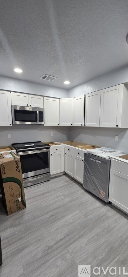 A kitchen with white cabinets and a grey floor.