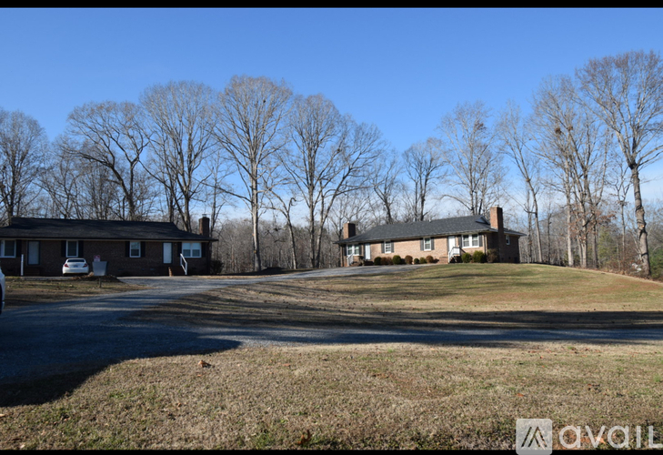 A house with a driveway and bare trees in the background.