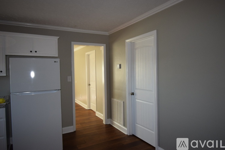 A kitchen with a white refrigerator and wooden floors.