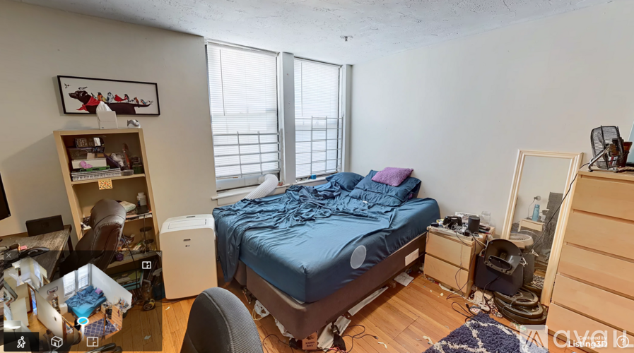 A bedroom with a bed, desk, chair, and window.
