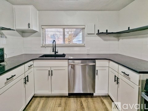 A kitchen with white cabinets and a black countertop.