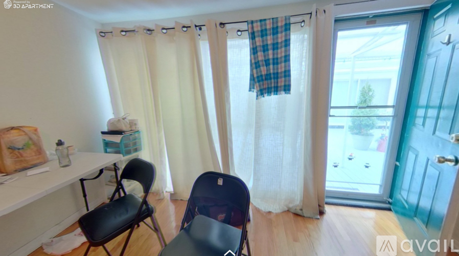 A room with a desk, two chairs, and a window with curtains.