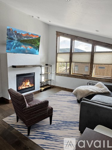 A living room with a fireplace and a painting of a mountain landscape on the wall.