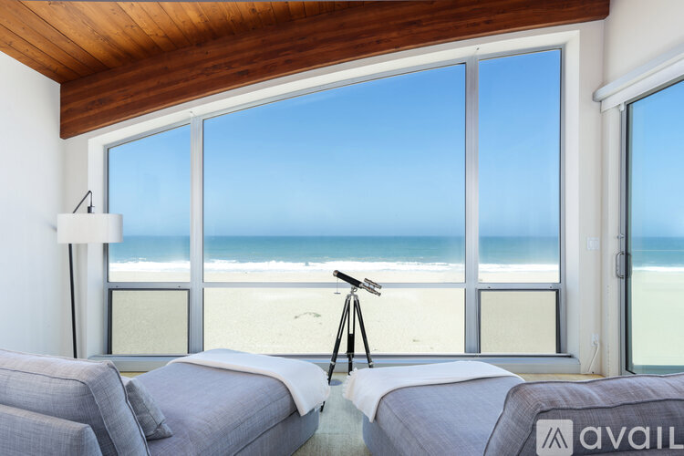 A room with a beach view through the windows.