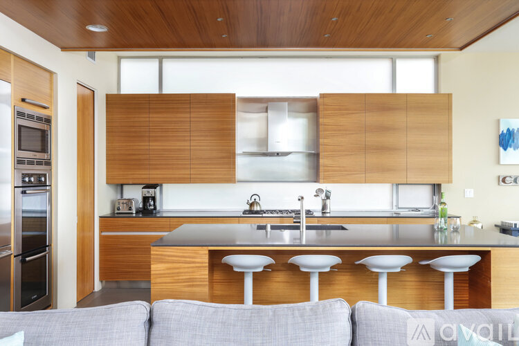 A modern kitchen with a grey sofa in front of it.