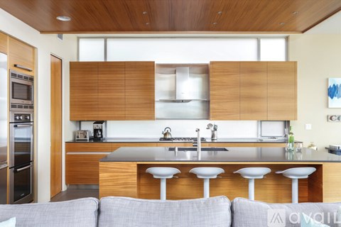 A modern kitchen with a grey sofa in front of it.