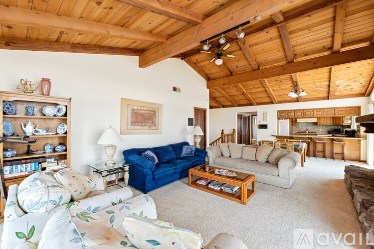 A living room with a blue couch and a wooden ceiling.
