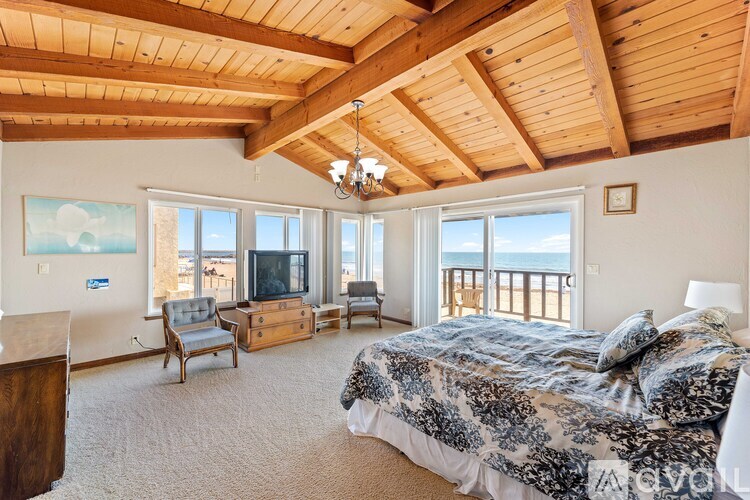 A bedroom with a large bed and a balcony overlooking the ocean.