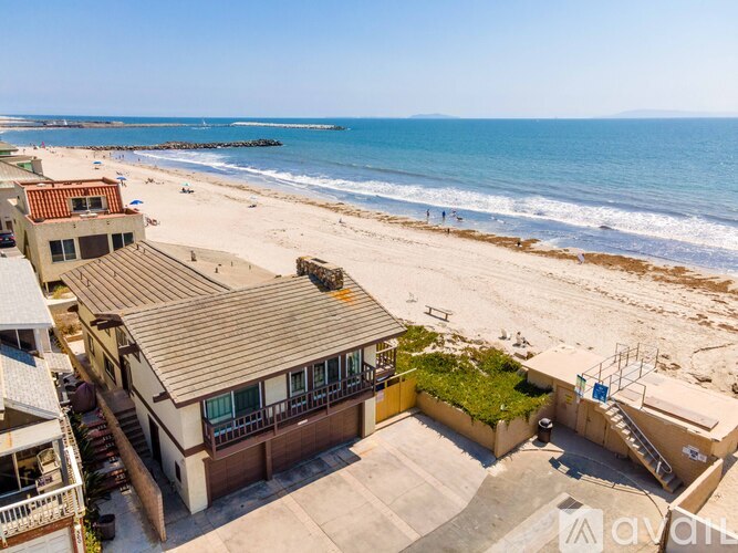 A beachfront property with a large open area and a building with a balcony overlooking the ocean.