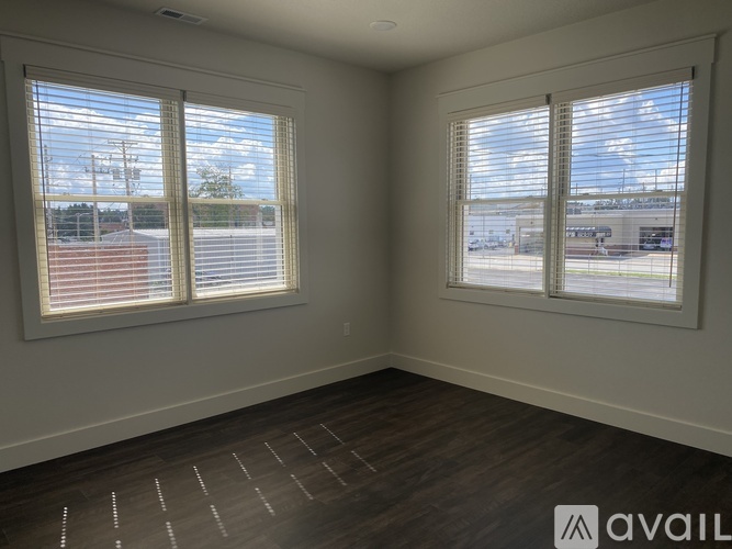 A room with two windows and wooden flooring.