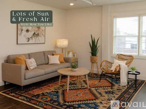 A living room with a grey sofa, a round table, a rug and a chair.
