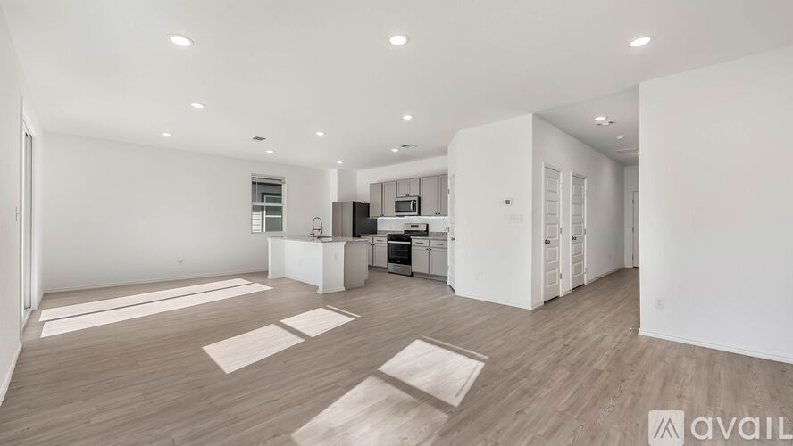 A spacious, empty room with wooden flooring and white walls.