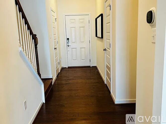 A hallway with a white door and a black and white picture on the wall.