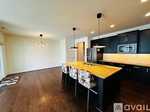 A kitchen with black cabinets and a wooden island with four chairs.