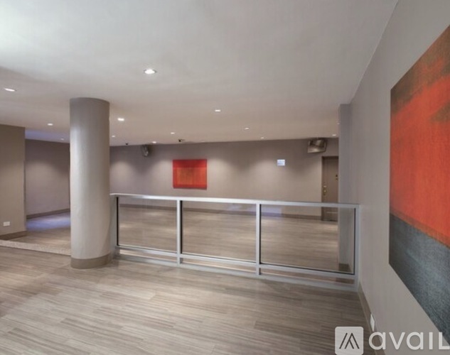 A hallway with a red painting on the wall and a glass railing.