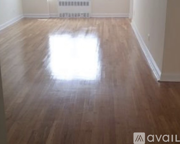 A room with wooden flooring and a radiator on the wall.